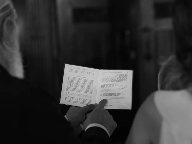 Hände halten während der Taufzeremonie ein geöffnetes liturgisches Buch