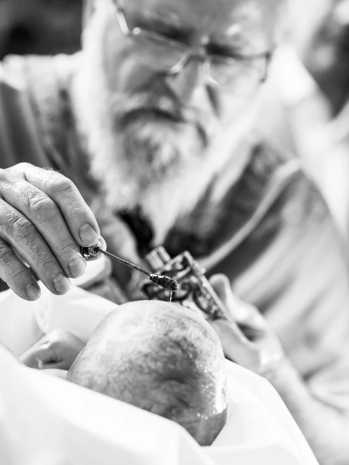 Priester salbt den Kopf eines Kindes während einer orthodoxen Taufe