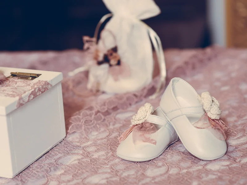 Weiße Taufschuhe und Geschenkbox vor der Zeremonie