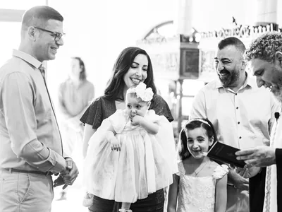Priester und Familie lachen mit dem Taufkind in der Kreuzerhöhungskirche Rüsselsheim