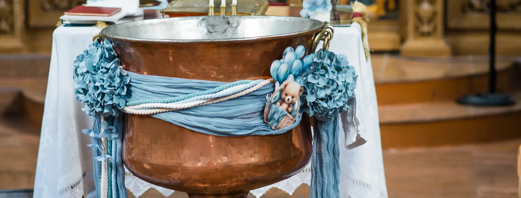 Mit blauen Blumen vorbereitetes Taufbecken in einer orthodoxen Kirche