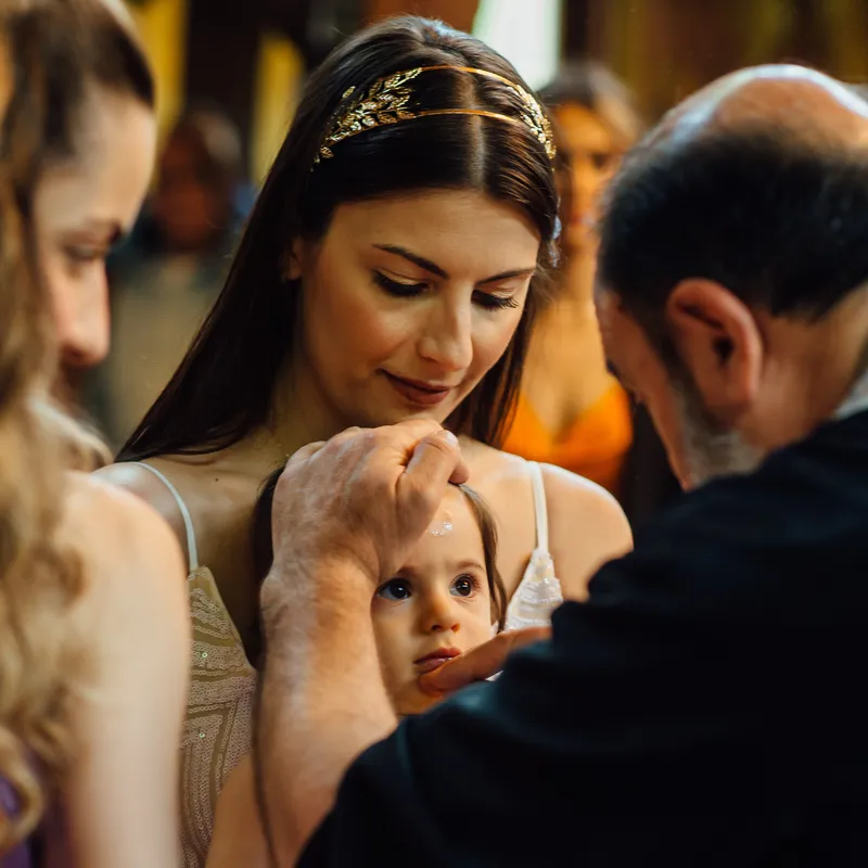 Priester salbt Stirn des Kindes mit Olivenöl bei orthodoxer Taufe - Taufe Fotograf Stuttgart