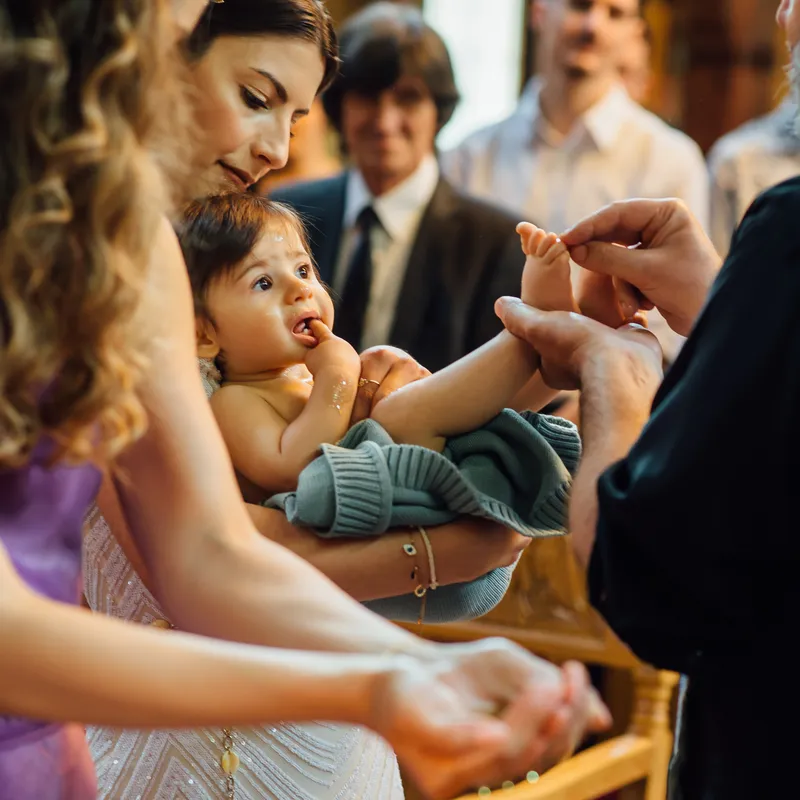Priester salbt die Füße des Täuflings mit Olivenöl bei orthodoxer Taufe - Taufe Fotograf Esslingen