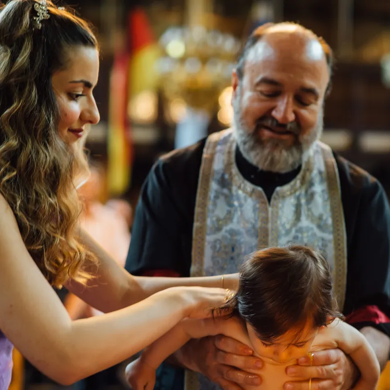 Patin salbt den Körper des Täuflings mit geweihtem Öl bei orthodoxer Taufe - Taufe Fotograf Esslingen