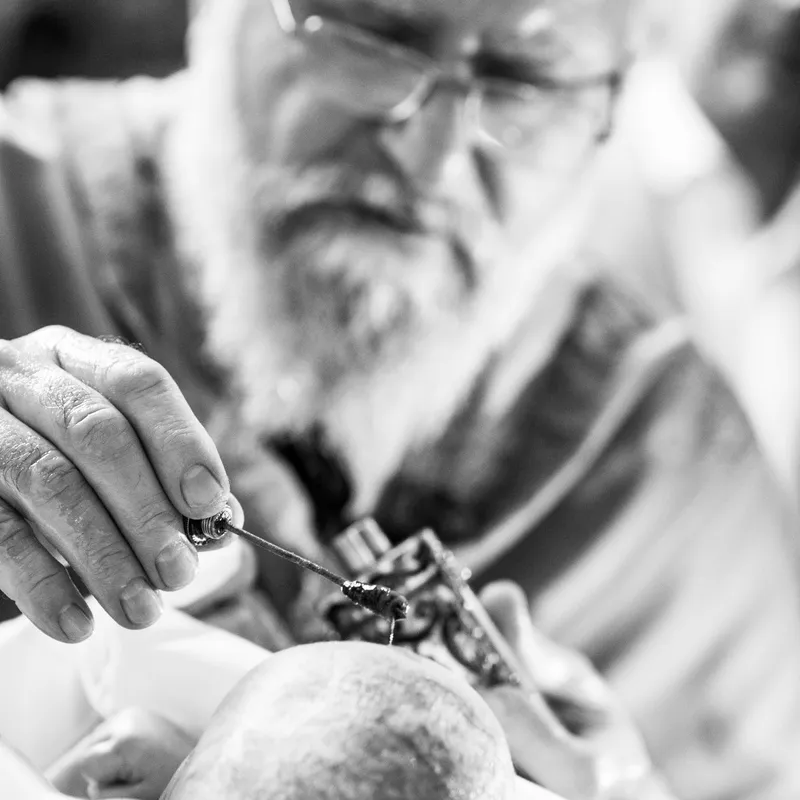 Priester salbt Kopf des Kindes mit Myron bei orthodoxer Taufe - Taufe Fotograf Esslingen
